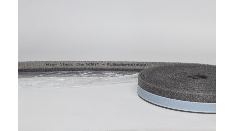 graue Rolle eines Schaumstoffstreifens mit blauer Klebefläche, auf dem Text zu einer Fußbodenheizungszone ("Hier liegt die NORIT Fußbodenheizzone") aufgedruckt ist.